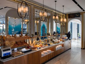 A hotel reception area with a buffet, chandeliers, and a sign indicating the lobby, reception, and restroom.
