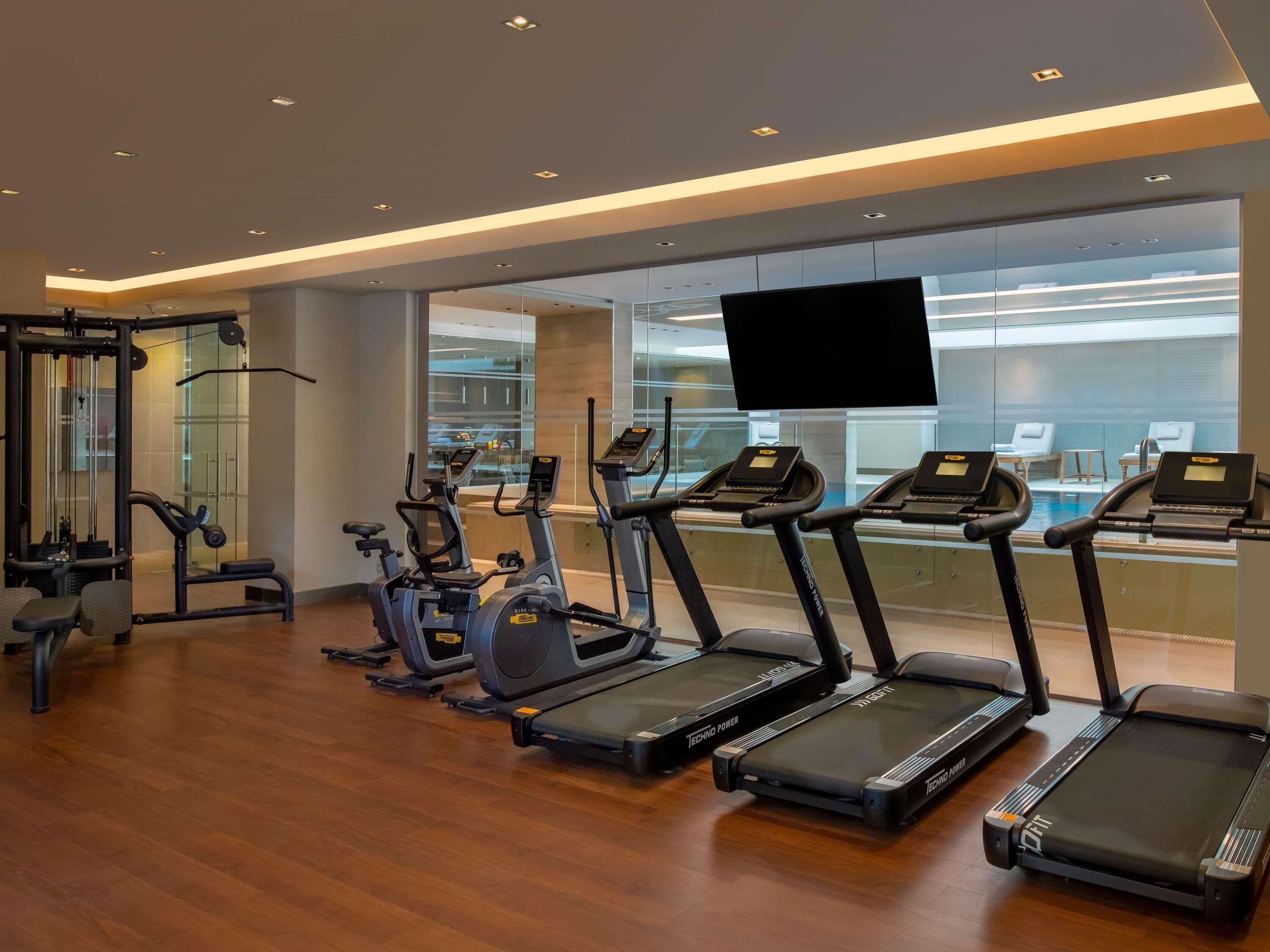 Une salle de sport équipée de tapis de course, de vélos elliptiques et de matériel de musculation.
