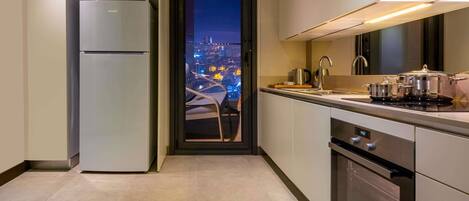 A modern kitchen with a built-in oven, a refrigerator, and a view of a cityscape at night.