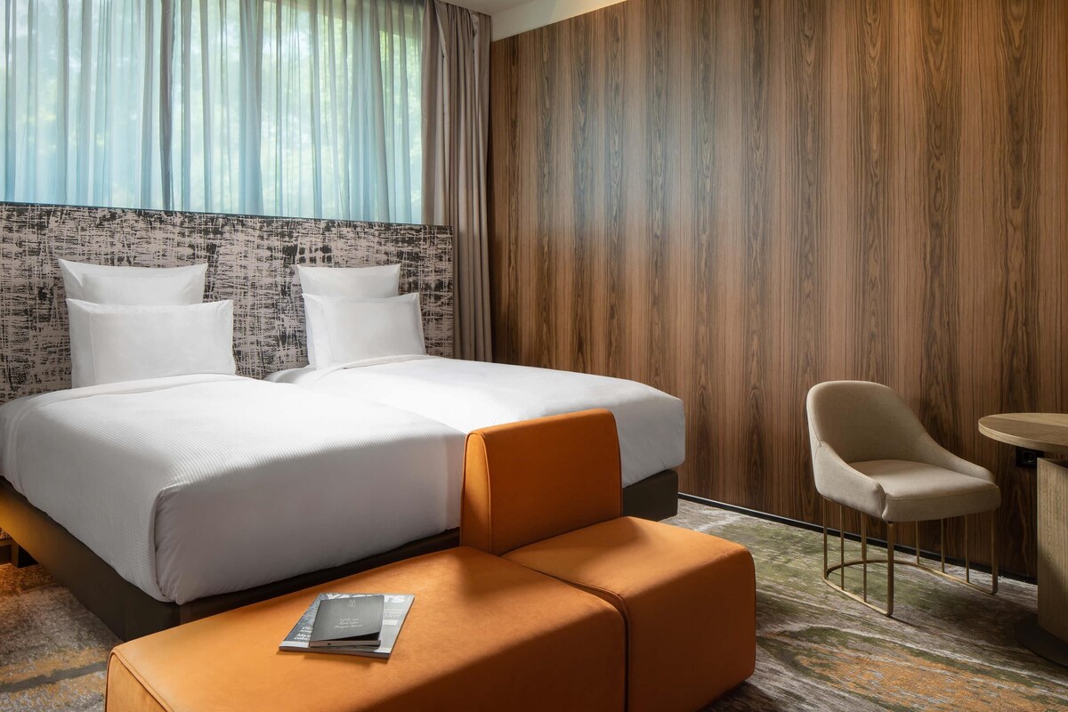 Una habitación de hotel con una cama grande, una mesita, una silla y un sofá.