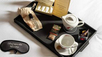 A tray with a tea set, a pack of cigarettes, a small bottle, and a pillow with a motivational quote.