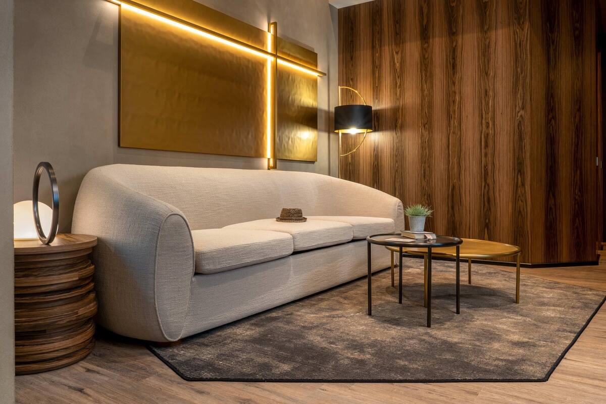 Uma sala de estar moderna com um sofá, uma mesa redonda pequena, um abajur e um painel de parede de madeira.