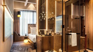 Une chambre d’hôtel moderne, équipée d’un lit, d’une table de chevet, d’une lampe et d’un grand miroir.