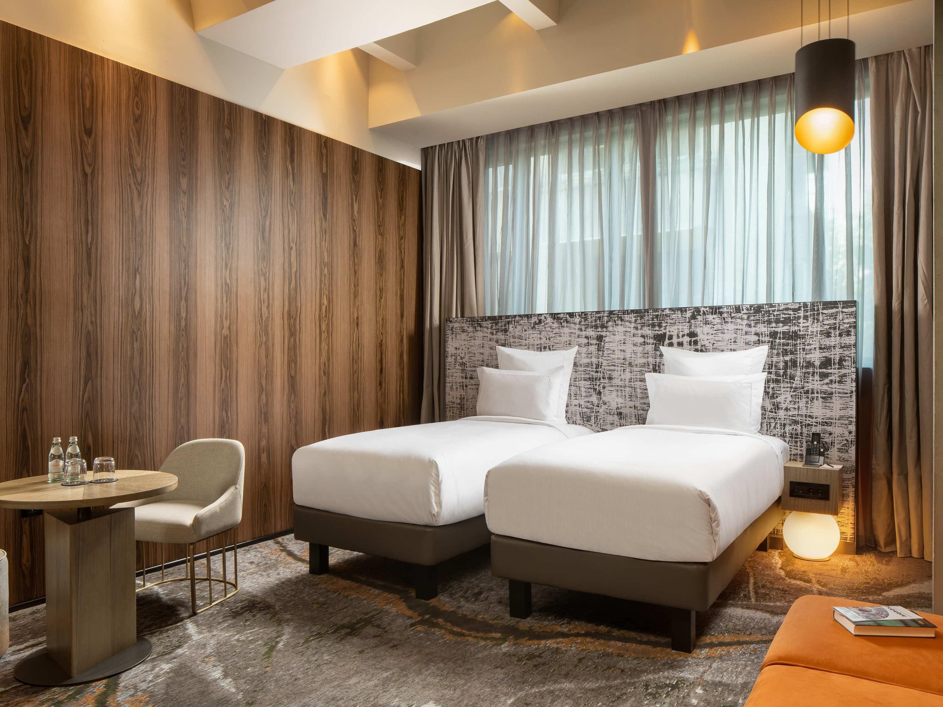 Una habitación de hotel con dos camas, un escritorio, una silla y una mesita.