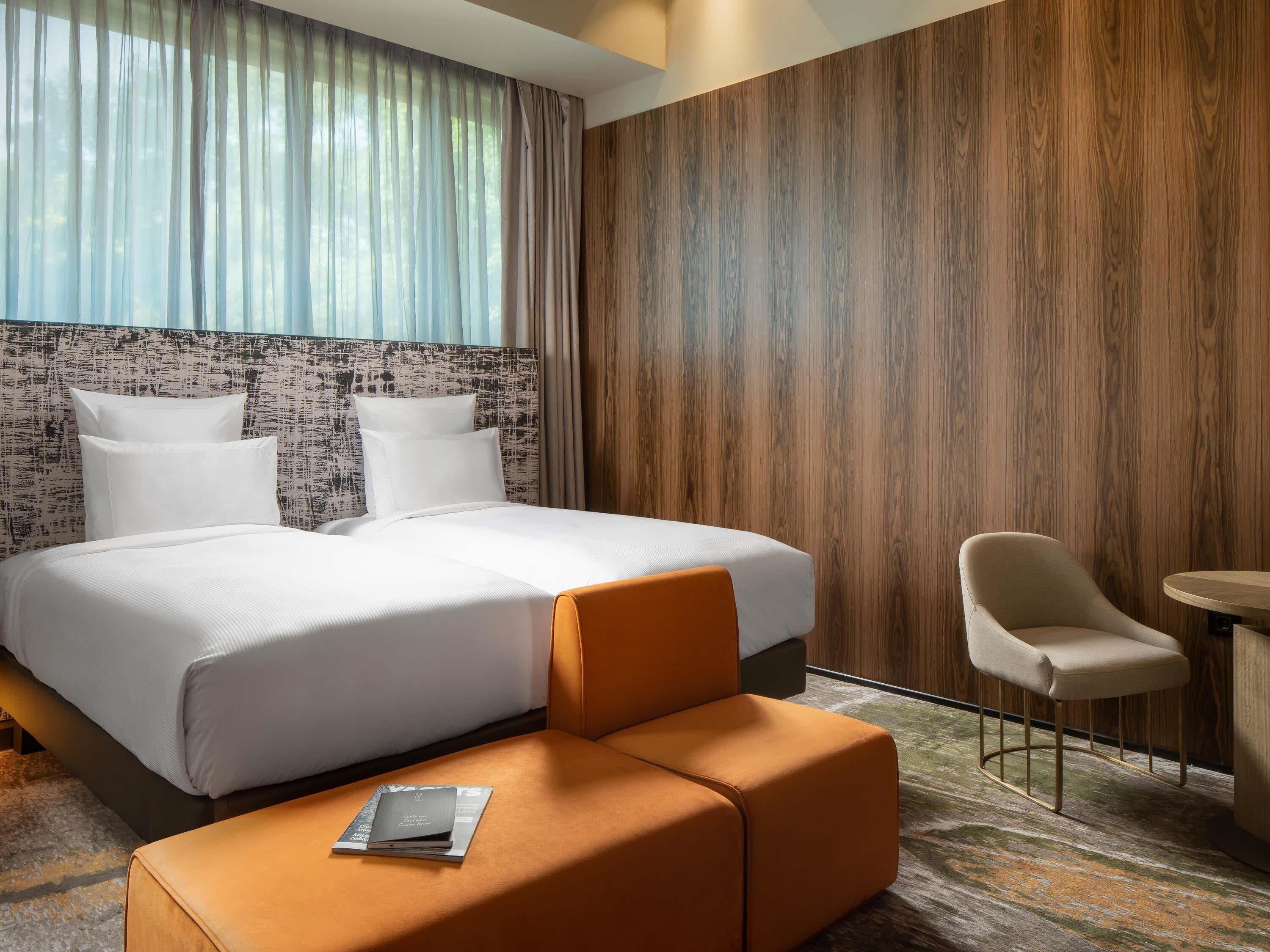 A hotel room with a large bed, a small table, a chair, and a sofa.