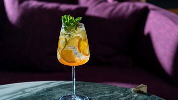 Et cocktailglas med citrusstykker og mynte på et marmorbord.