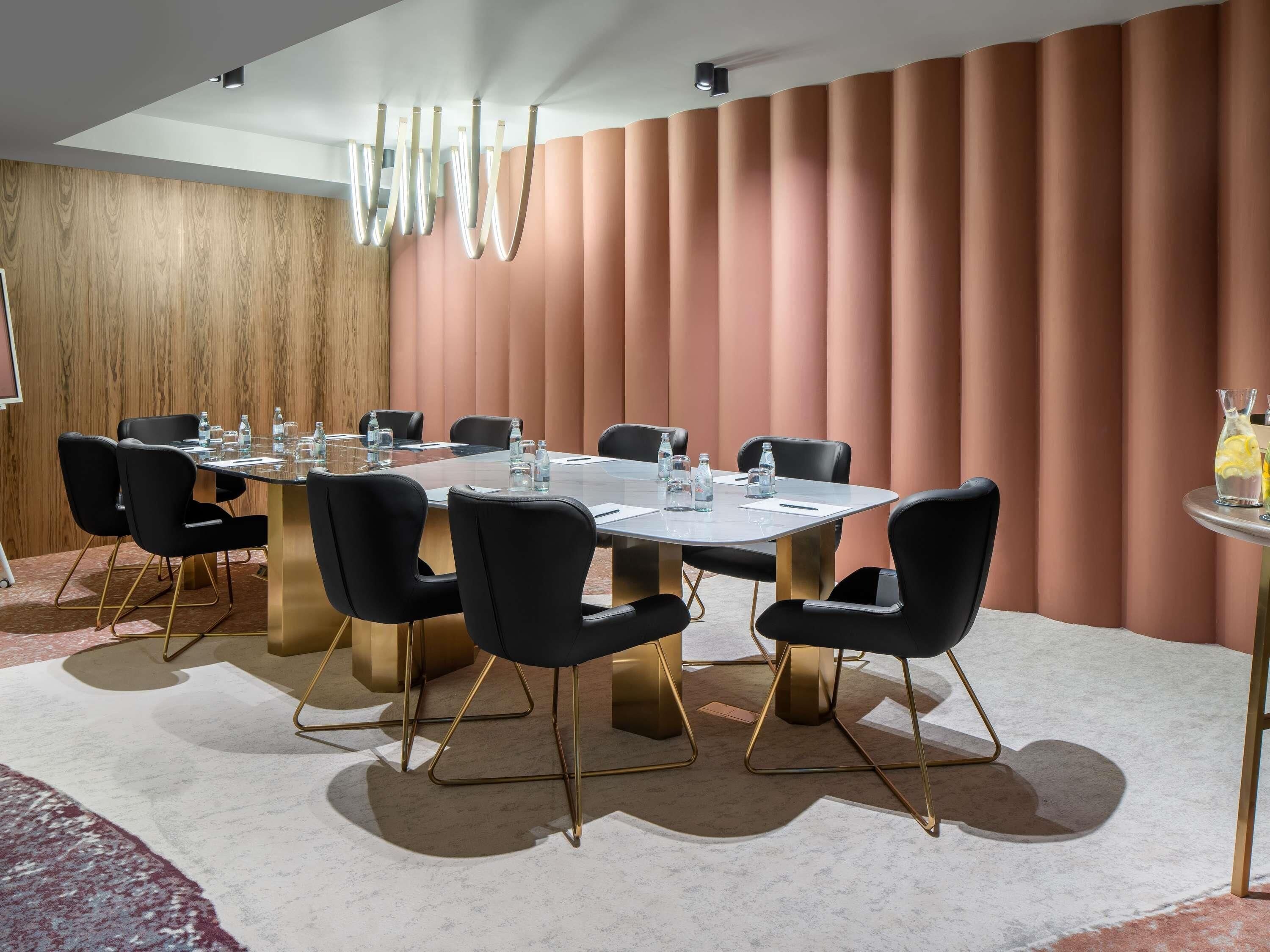 Una sala conferenze con un tavolo grande, sedie nere e una parete rivestita in legno.