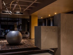 Een modern interieur met een grote, bolvormige sculptuur, een receptiebalie met de tekst 'TORRO' en een houten vloer.