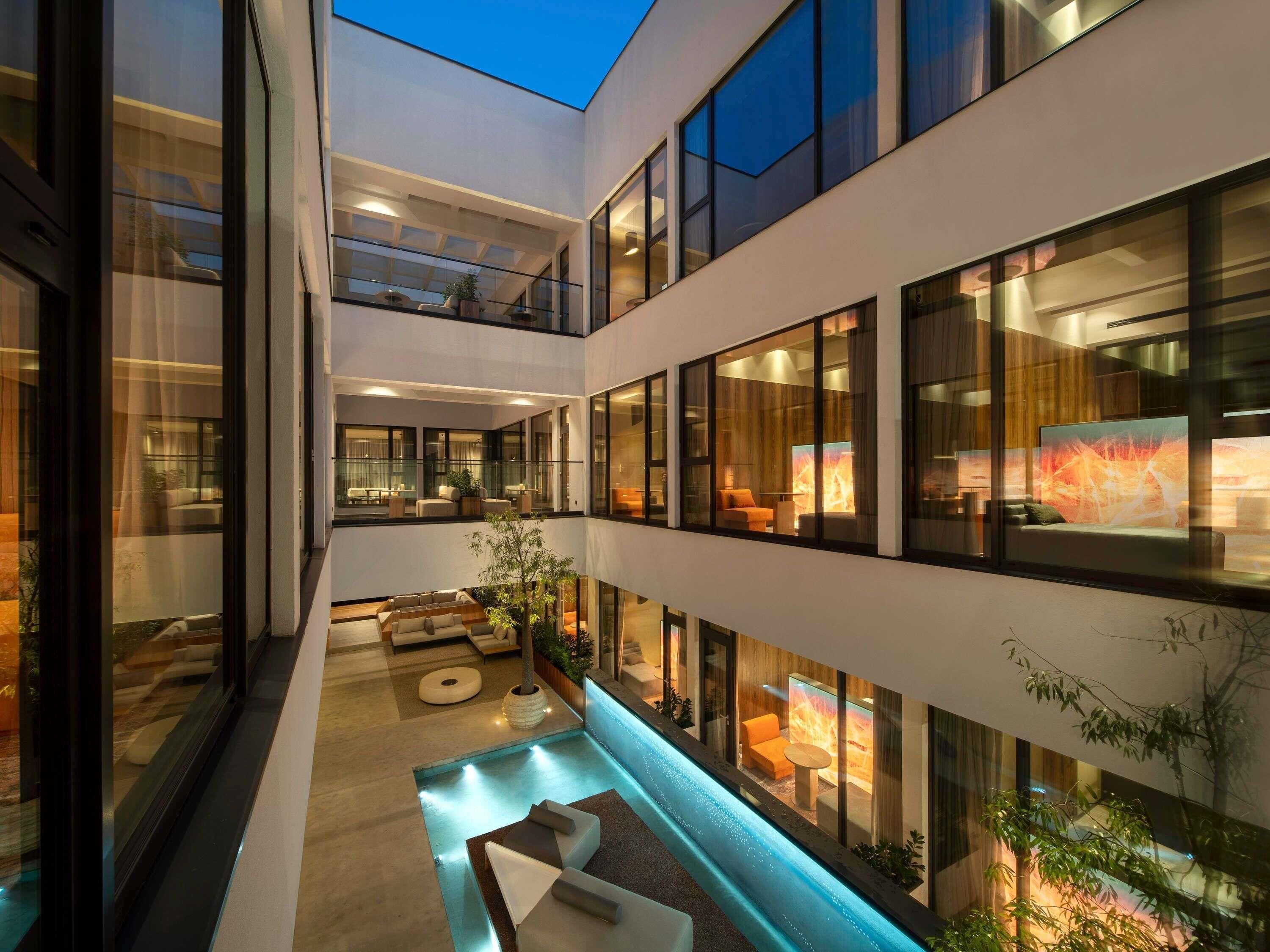A modern building with multiple floors, large windows, and a central courtyard with seating and a water feature.