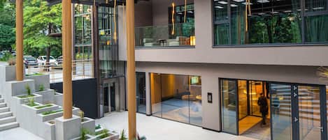 A modern building with a spacious atrium, concrete planters, and large windows.