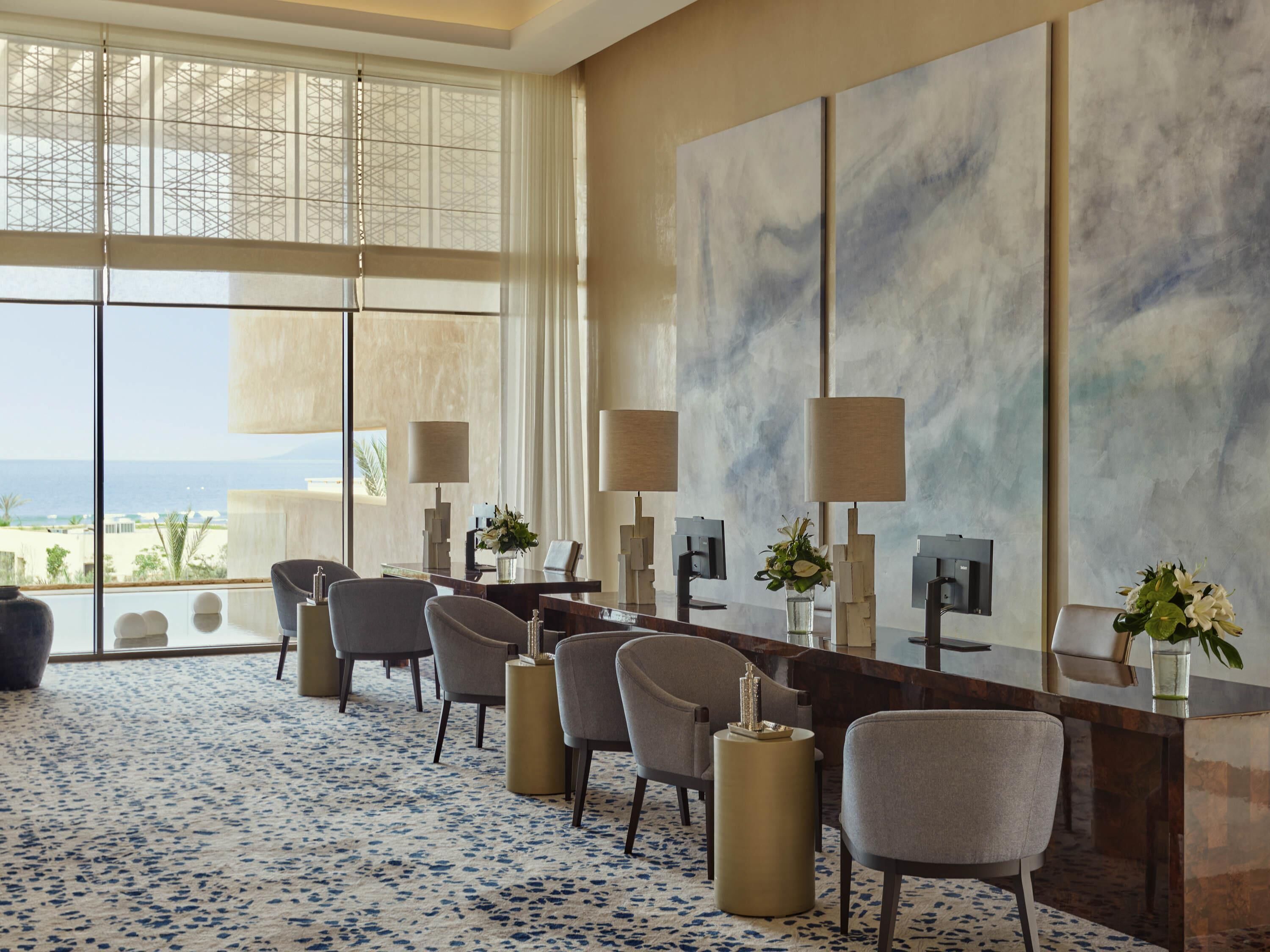 Habitación de hotel con un ventanal grande, un área de comedor con sillas y una mesa, y un cuadro abstracto de gran tamaño en la pared.