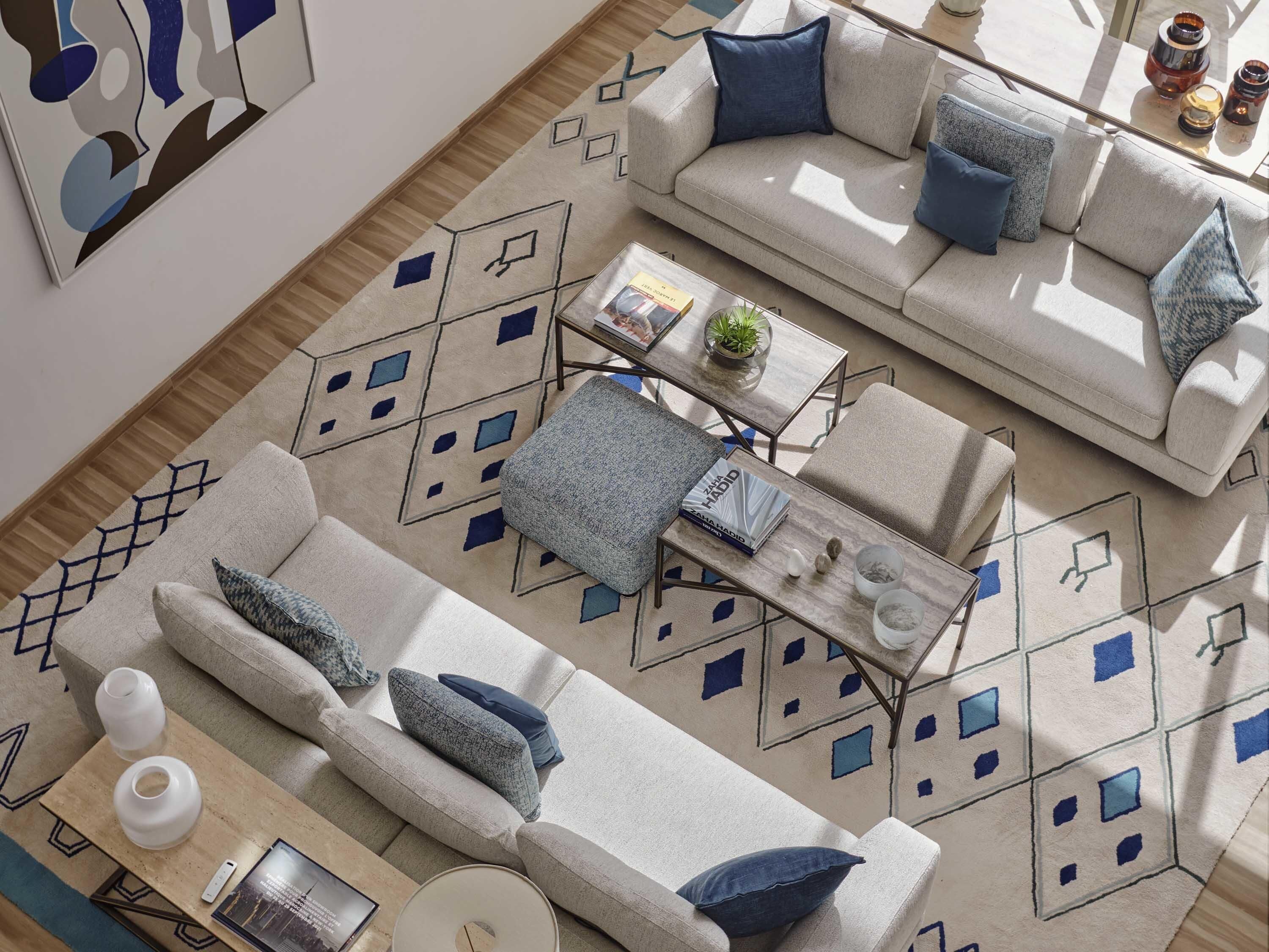 Een moderne woonkamer met een bank, voetenbankje, salontafel en decoratieve objecten.