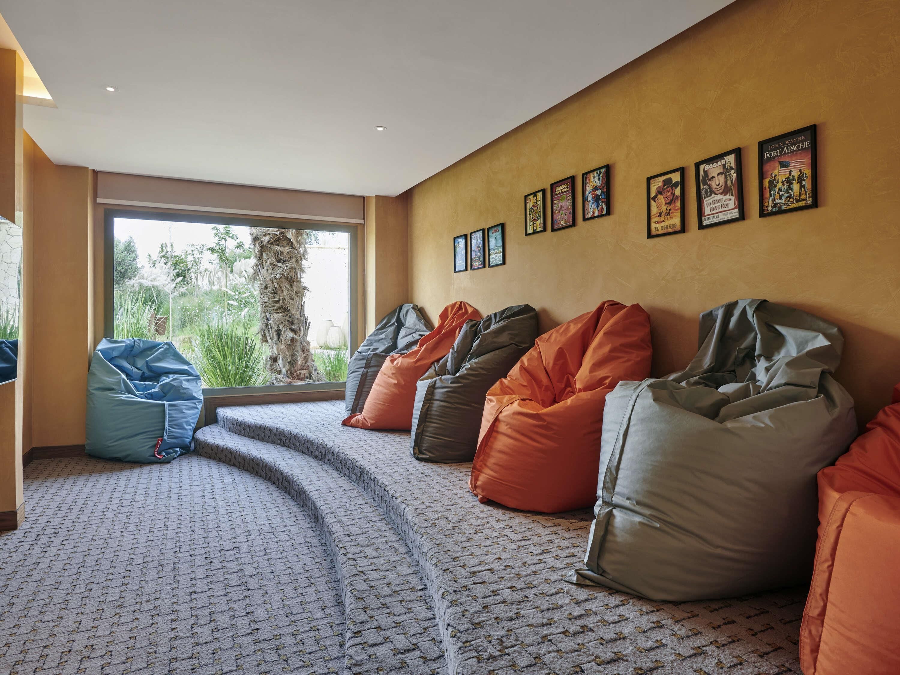 A room with bean bags, a patterned carpet, a large window, and framed posters on the wall.