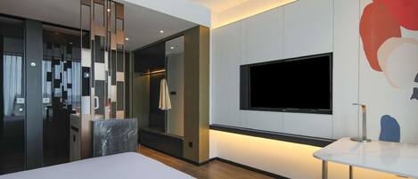 A modern hotel room with a large bed, a TV mounted on the wall, and a small table.