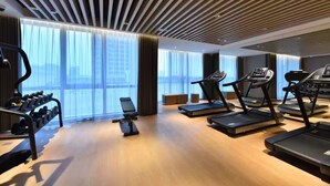 A modern gym with treadmills, a rowing machine, and dumbbells.