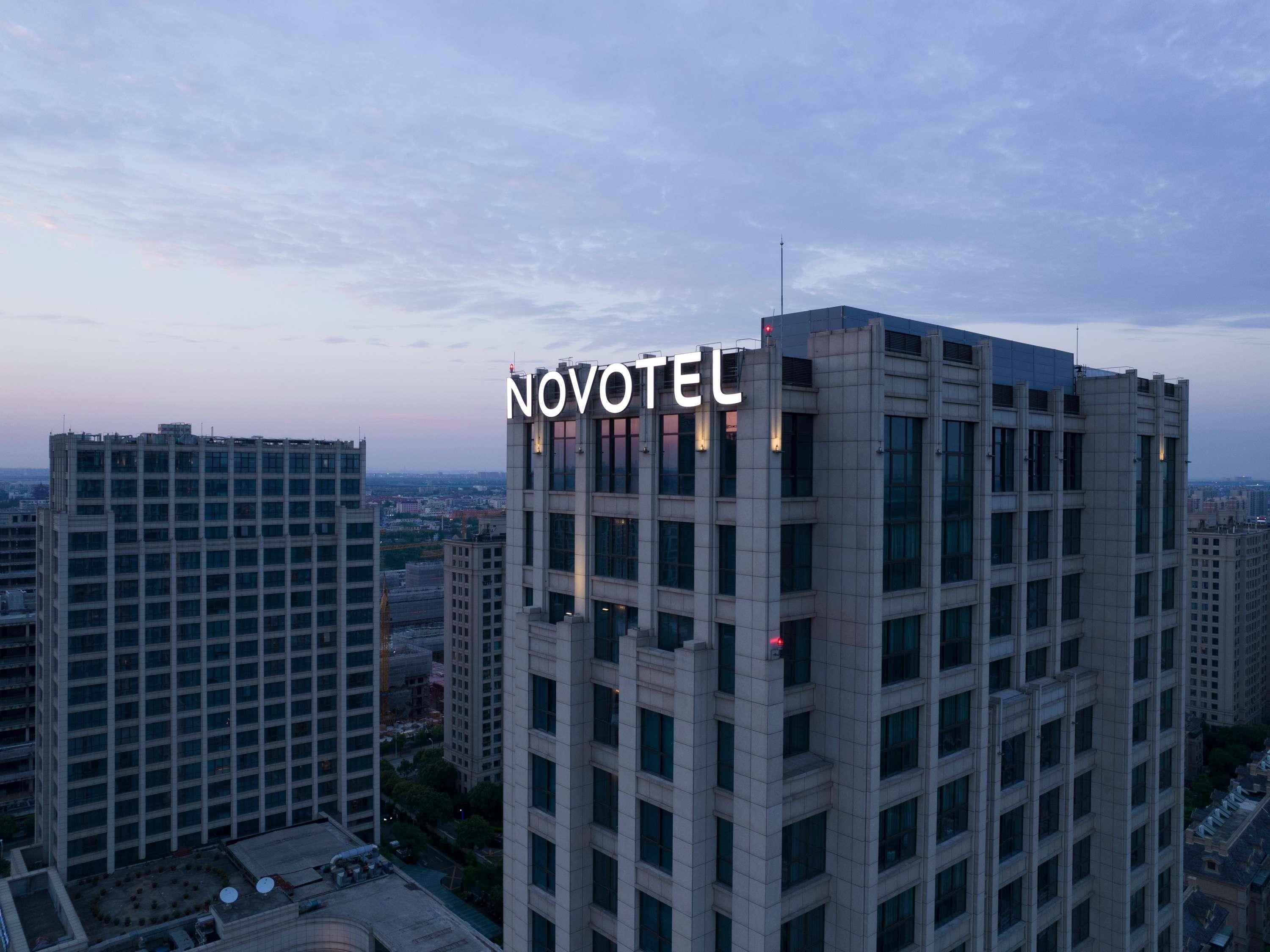 A high-rise hotel with the name NOVOTEL prominently displayed on its facade.