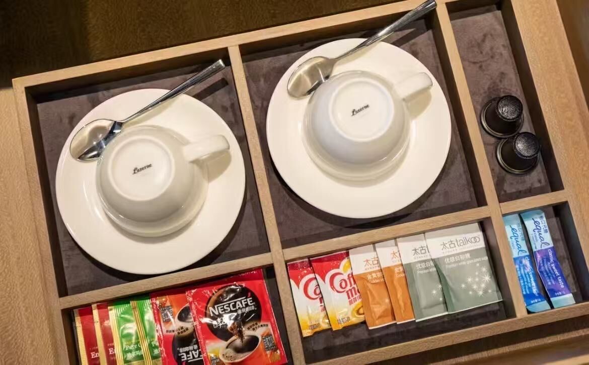 Un tiroir contenant deux tasses blanches, une cuillère et diverses capsules de café.