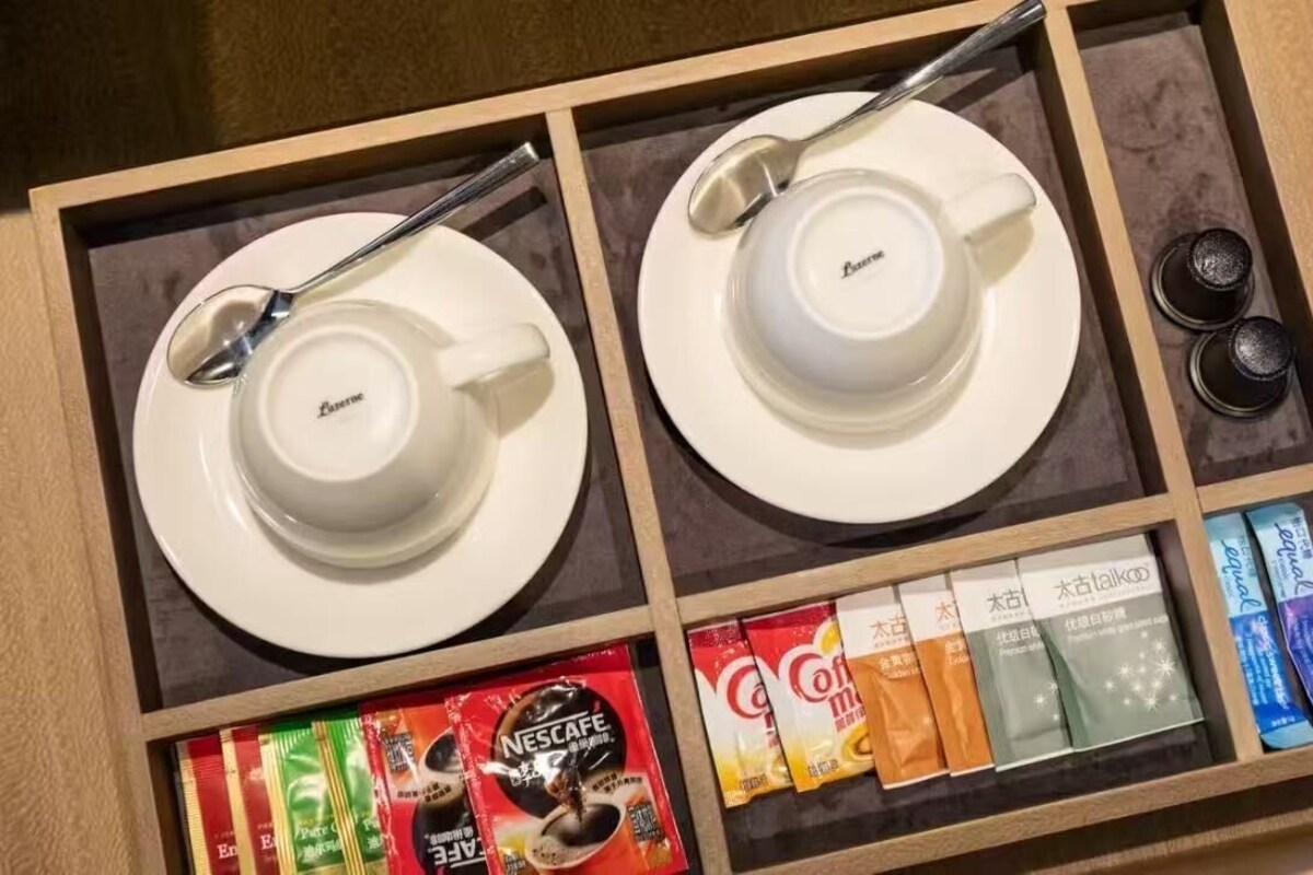 A drawer with two white cups, a spoon, and various coffee pods.