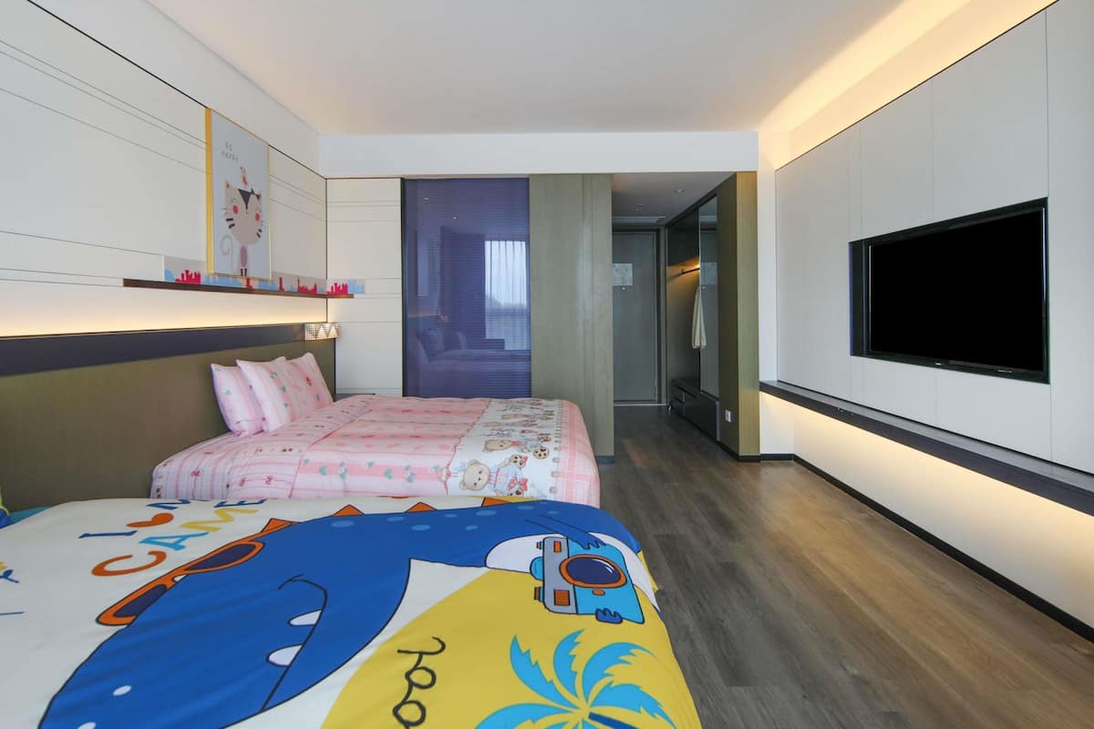 A bedroom with a bed, a TV, a mirror, and a door leading to a bathroom.