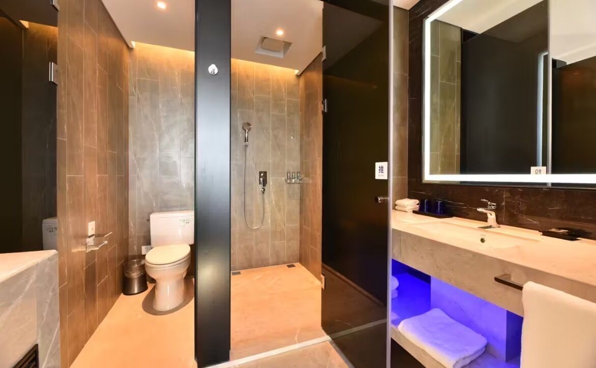 A modern bathroom with a toilet, shower, and vanity with a mirror.