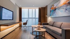 A modern hotel room with a large window, a sofa, a desk with a computer, and a painting on the wall. - Novotel Shanghai Chuansha (Shanghai)