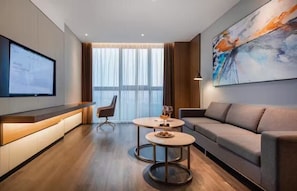 A modern hotel room with a large window, a sofa, a desk with a computer, and a painting on the wall. - Novotel Shanghai Chuansha (Shanghai)