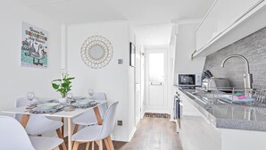 A modern kitchen with a built-in stove, a sink, and a countertop. There is a dining area with a table and chairs.