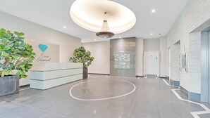 Un área de recepción moderna con un diseño de piso circular, una araña y plantas en macetas.