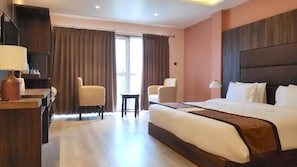 A hotel room with a large bed, two armchairs, a desk with a lamp, and a view of the outdoors through the window. - Jewel Kongchen Retreat & Spa (Chungthang)