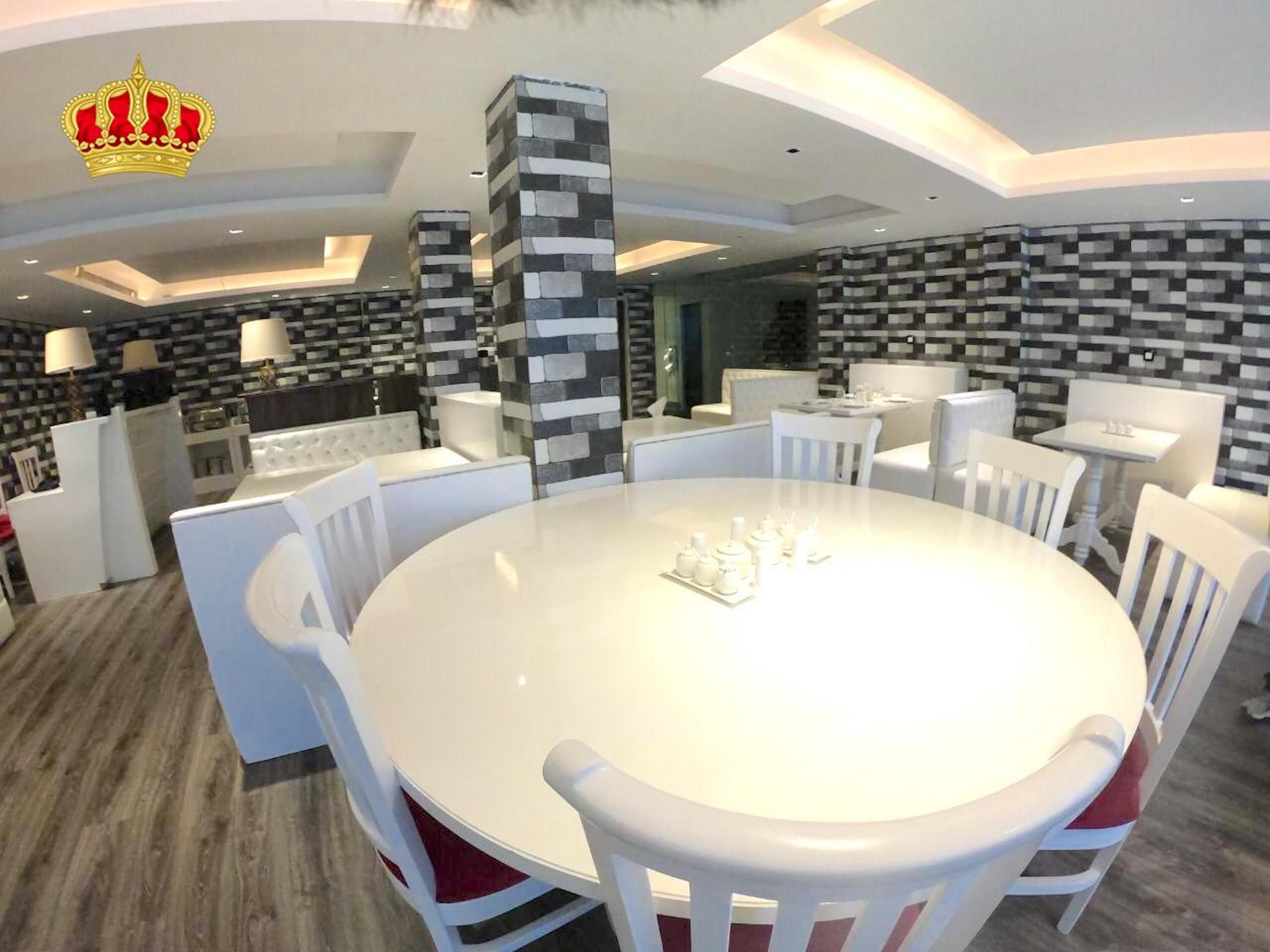 A modern dining area with a round table, white chairs, and a central pillar.