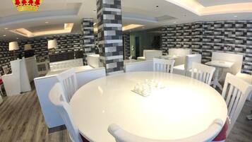 A modern dining area with a round table, white chairs, and a central pillar.