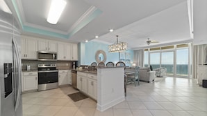 A modern kitchen with white cabinets, stainless steel appliances, and a large island. - Phoenix Orange Beach II 1404 by Liquid Life (Orange Beach)