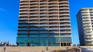 A tall, modern hotel with a distinctive curved facade and multiple balconies. - Phoenix Orange Beach II 1404 by Liquid Life (Orange Beach)