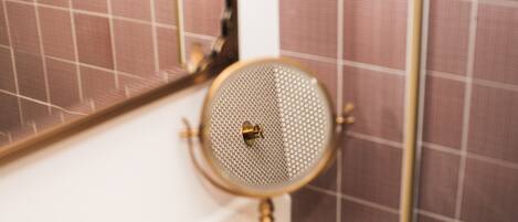 Un bagno con uno specchio tondo fissato a una parete bianca, una base dorata e un pavimento a scacchi sullo sfondo.