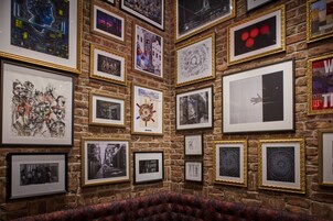 A wall with various framed artworks and a patterned carpet.