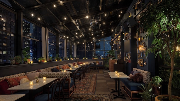A modern restaurant with a long counter, multiple seating areas, and large windows overlooking a cityscape.