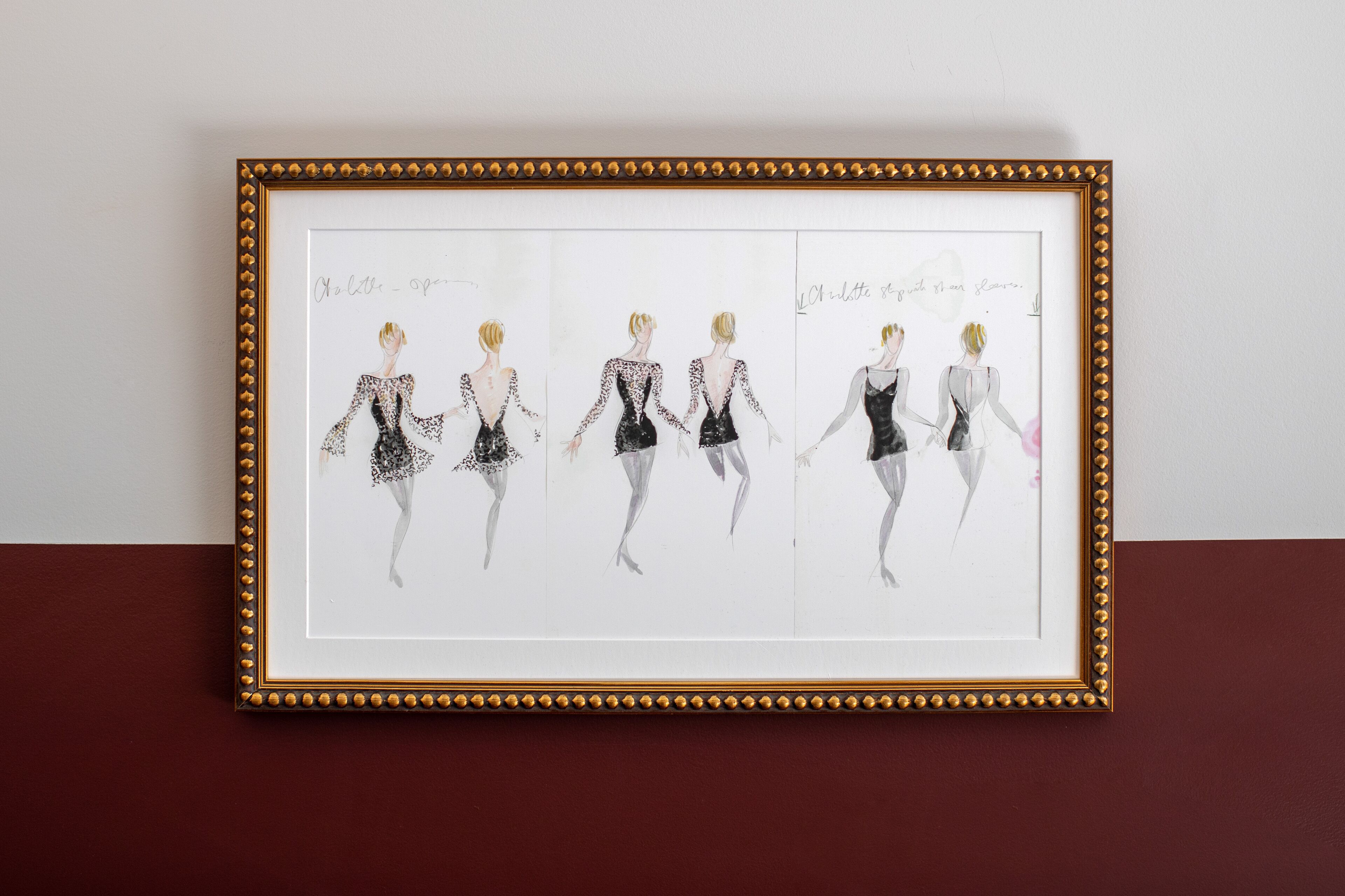 Una obra de arte enmarcada que muestra cinco figuras en distintas poses, cada una vestida con atuendos diferentes.