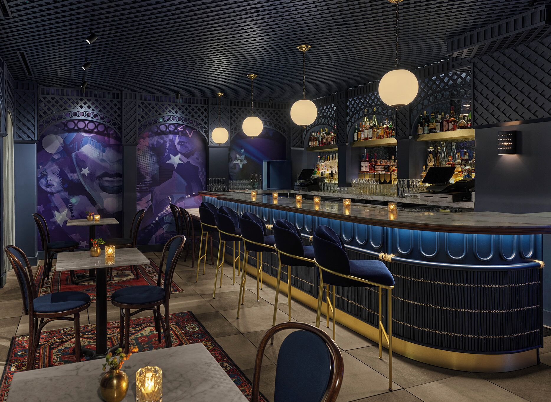Eine Bar mit einer gebogenen Theke, Barhocker und einer gemusterten Decke.