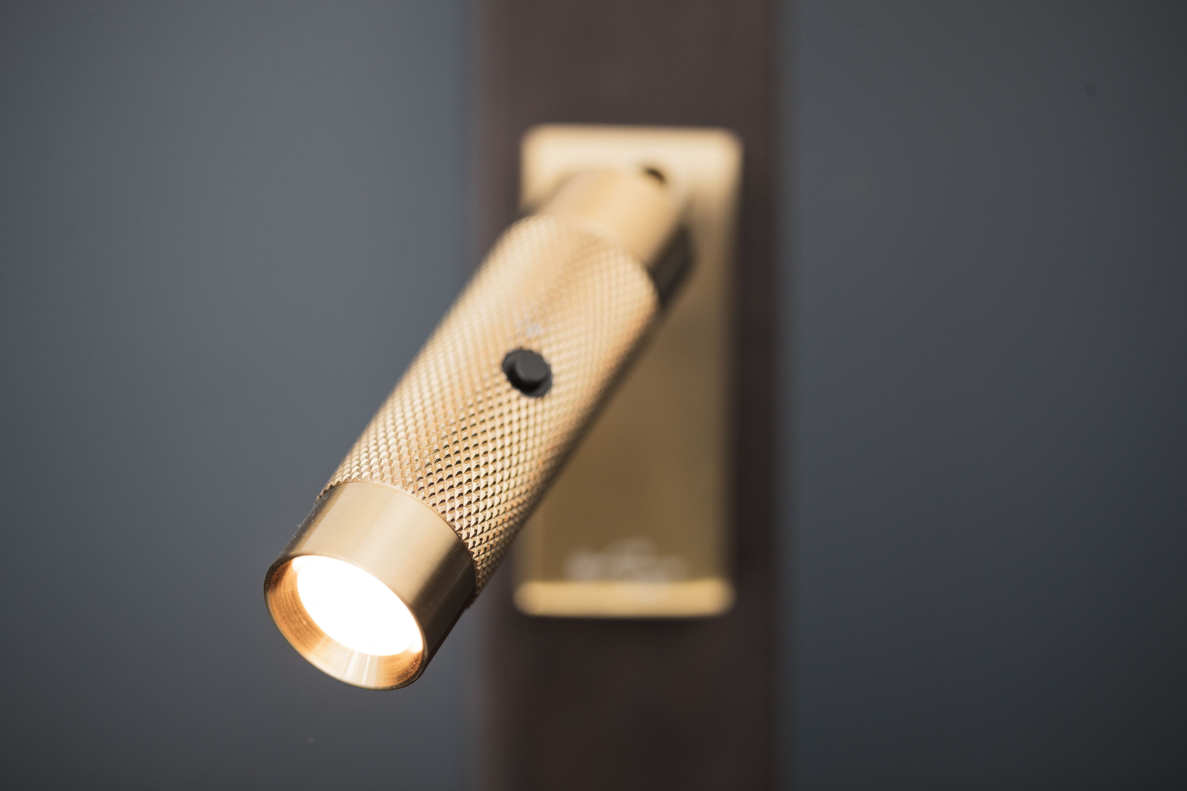 A close-up of a wall-mounted light fixture with a textured cylindrical handle and a visible switch.