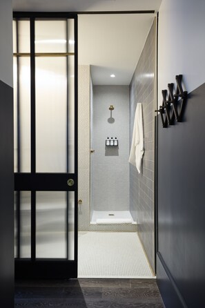 A modern bathroom with a walk-in shower, tiled walls, and a towel rack. - CIVILIAN Hotel (New York)