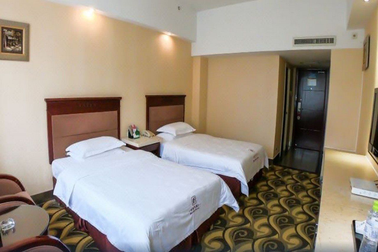A hotel room with two beds, a desk with a chair, a telephone, and a television.