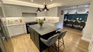 A modern kitchen with white cabinets, a central island, bar stools, and pendant lighting. - Beautiful Large Country Barn Conversion Hot Tub, Pool, BBQ Hut, Large Grounds (Lampeter)
