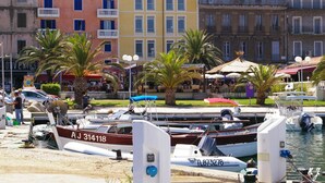 A marina with boats docked, palm trees, and buildings with balconies. - U Palmu, Sea 6 km, Panoramic view, Garden, Wifi, Air-conditioned (Sartène)