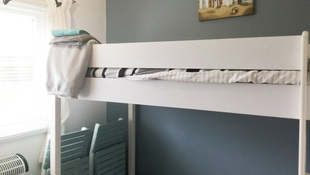 Een stapelbed met een handdoek aan de linkerkant en een schilderij erboven.