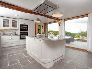 Une cuisine moderne dotée d’un grand îlot central, d’appareils électroménagers intégrés et donnant sur une terrasse extérieure.