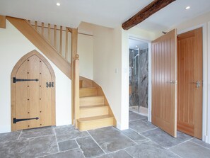 Un escalier en bois menant à un deuxième étage, une cabine de douche en verre et une porte en bois.