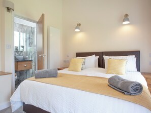 A hotel room with a bed, bedside lamps, a bathroom with a mirror, and a towel on the bed. - 3 bedroom accommodation in South Tawton, near Okehampton (South Tawton, near Okehampton)