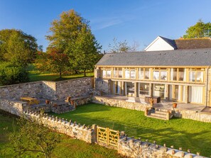 A stone building with a covered patio area, stone walls, and a grassy lawn. - 3 bedroom accommodation in South Tawton, near Okehampton (South Tawton, near Okehampton)