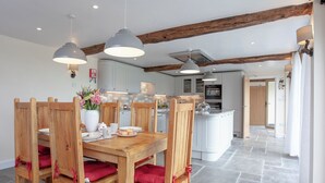 Een moderne keuken met witte kasten, een centraal eiland en houten stoelen met rode kussens.