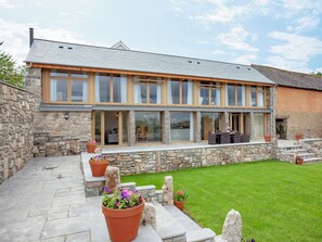 A two-story house with a stone exterior, large windows, and a covered patio area. - 3 bedroom accommodation in South Tawton, near Okehampton (South Tawton, near Okehampton)